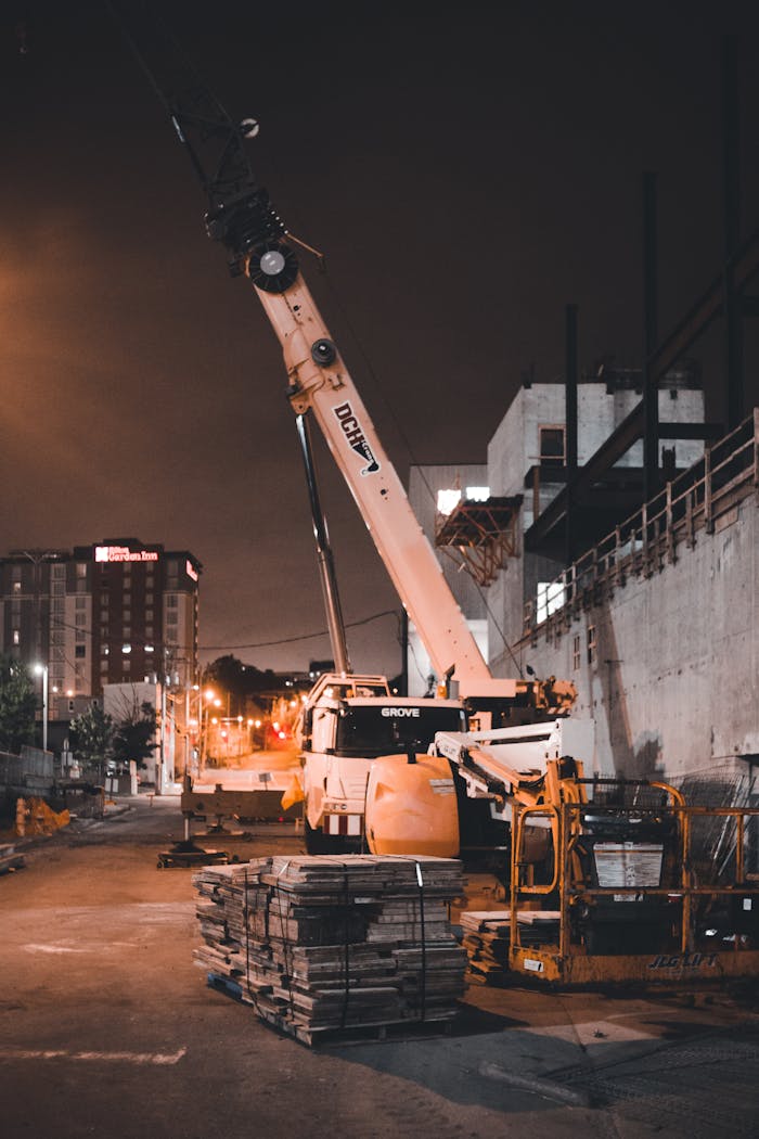 A crane operates at an urban construction site during the evening, highlighting industrial progress.